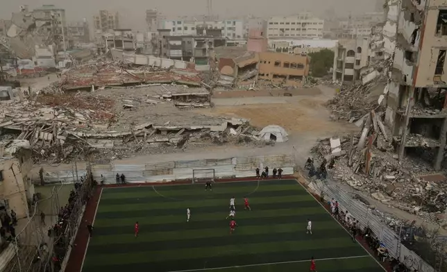 Palestinian players of Gaza Sports Club and Al-Ahly Club take part in a soccer match at a newly constructed field surrounded by buildings destroyed in Israeli ground and air operations, in Gaza City, Saturday, Feb. 14, 2026. (AP Photo/Jehad Alshrafi)