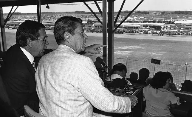 FILE - President Ronald Reagan, front right, sits with William France Jr., president of NASCAR and part owner of the Daytona Speedway, and watches the running of the Firecracker 400 stock car race July 4, 1984, in Daytona Beach, Fla. (AP Photo/Ira Schwarz, File)