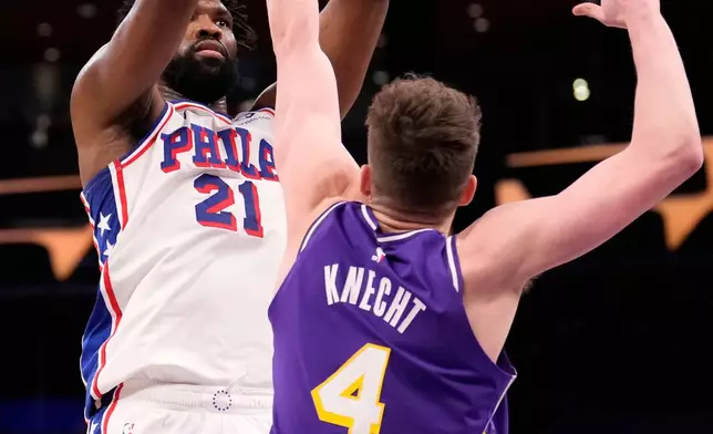 Philadelphia 76ers center Joel Embiid, left, shoots as Los Angeles Lakers forward Dalton Knecht defends during the first half of an NBA basketball game Thursday, Feb. 5, 2026, in Los Angeles. (AP Photo/Mark J. Terrill)