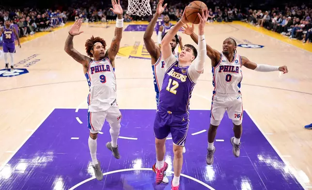 Los Angeles Lakers forward Jake LaRavia, second from right, shoots as Philadelphia 76ers guard Kelly Oubre Jr., left, center Joel Embiid, second from lef and guard Tyrese Maxey defend during the first half of an NBA basketball game Thursday, Feb. 5, 2026, in Los Angeles. (AP Photo/Mark J. Terrill)