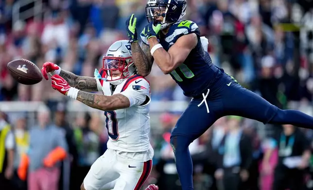 New England Patriots cornerback Christian Gonzalez (0) breaks up a pass intended for Seattle Seahawks wide receiver Jaxon Smith-Njigba, right, during the first half of the NFL Super Bowl 60 football game, Sunday, Feb. 8, 2026, in Santa Clara, Calif. (AP Photo/Sue Ogrocki)