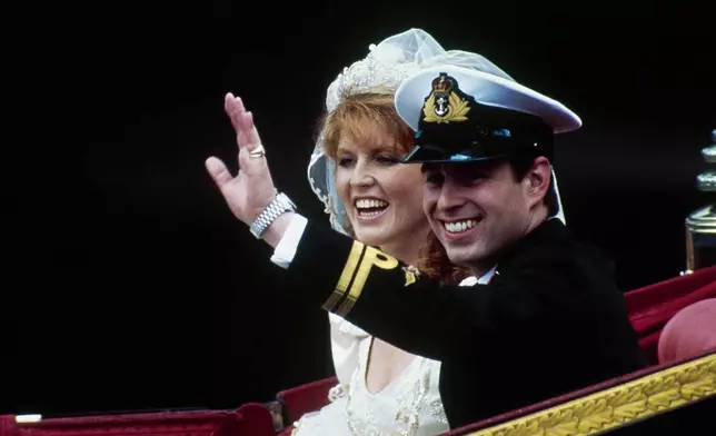 FILE - British Prince Andrew, with his bride, Sarah, waves from their horse-drawn carriage as they leave Westminster Abbey following their marriage in London, July 23, 1986. (AP Photo/Dave Caulkin, File)