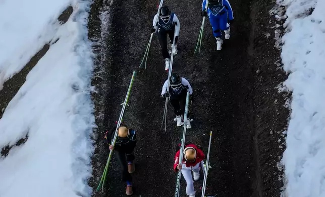 Athletes make their way to the ramp during the ski jumping women's large hill individual at the 2026 Winter Olympics, in Predazzo, Italy, Sunday, Feb. 15, 2026. (AP Photo/Evgeniy Maloletka)