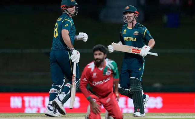 Australia's Travis Head and captain Mitchell Marsh run between the wickets as Oman's Jay Odedra, centre, dives to field a ball during the T20 World Cup cricket match between Australia and Oman in Pallekele, Sri Lanka, Friday, Feb. 20, 2026. (AP Photo/Eranga Jayawardena)
