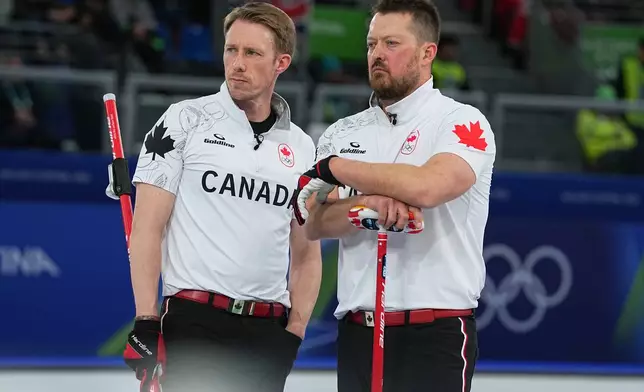 Canada's Marc Kennedy and Ben Hebert watch action in a men's curling semifinal match against Norway at the 2026 Winter Olympics, in Cortina d'Ampezzo, Italy, Thursday, Feb. 19, 2026. (AP Photo/Fatima Shbair)