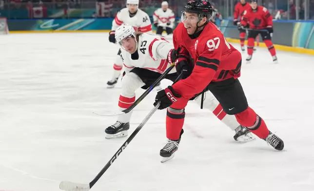Switzerland's Michael Fora, left, challenges Canada's Connor McDavid during a preliminary round match of men's ice hockey between Canada and Switzerland at the 2026 Winter Olympics, in Milan, Italy, Friday, Feb. 13, 2026. (AP Photo/Hassan Ammar)