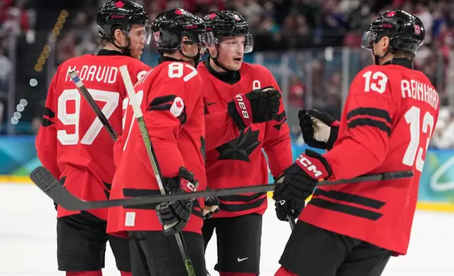 Canada's Cale Makar (8) celebrates with teammates Canada's Connor McDavid (97), Canada's Sidney Crosby (87), Canada's Sam Reinhart (13) after scoring during a preliminary round game of men's ice hockey between Canada and France at the 2026 Winter Olympics, in Milan, Italy, Sunday, Feb. 15, 2026. (AP Photo/Hassan Ammar)