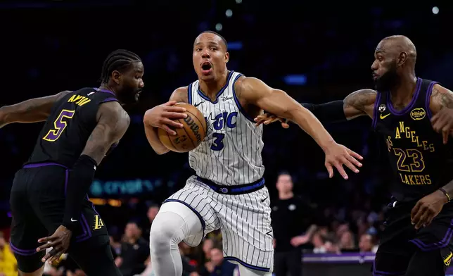 Orlando Magic guard Desmond Bane (3) dribbles with the ball past Los Angeles Lakers center Deandre Ayton (5) and Los Angeles Lakers forward LeBron James (23) during the first half of an NBA basketball game, Tuesday, Feb. 24, 2026, in Los Angeles. (AP Photo/Caroline Brehman)