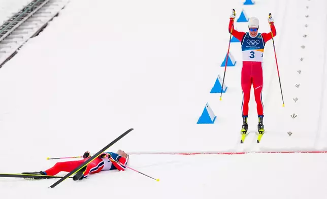 Martin Loewstroem Nyenget, of Norway, crosses the finish line to win the silver medal, behind Johannes Hoesflot Klaebo, also of Norway, in the cross country skiing men's 50km mass start Classic at the 2026 Winter Olympics, in Tesero, Italy, Saturday, Feb. 21, 2026. (AP Photo/Kirsty Wigglesworth)
