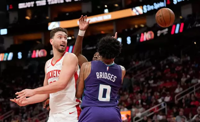Houston Rockets center Alperen Sengun, left, passes the ball over his back against Charlotte Hornets forward Miles Bridges (0) during the first half of an NBA basketball game, Thursday, Feb. 5, 2026, in Houston. (AP Photo/ Karen Warren)