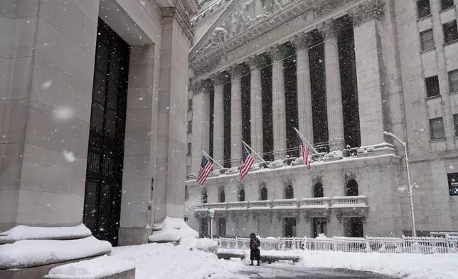 A pedestrian walks outside the New York Stock Exchange during a snow storm, Monday, Feb. 23, 2026, in New York. (AP Photo/Seth Wenig)