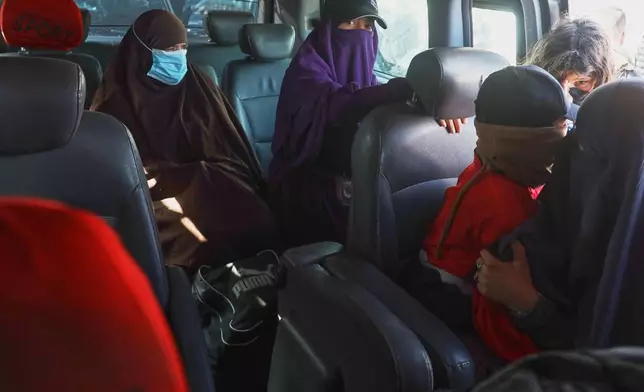 Family members of suspected Islamic State militants who are Australian nationals sit in a van heading to the airport in Damascus during the first repatriation operation of the year, at Roj Camp in eastern Syria, Monday, Feb. 16, 2026. Thirty-four Australian citizens from 11 families departed the camp. (AP Photo/Baderkhan Ahmad)