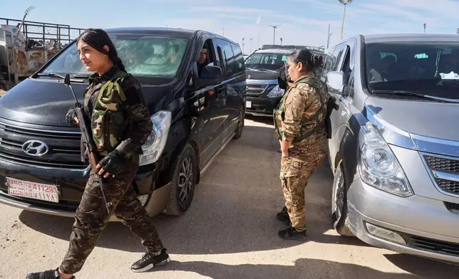 Female members of the Syrian Democratic Forces secure the area as vans carrying family members of suspected Islamic State militants who are Australian nationals head to the airport in Damascus during the first repatriation operation of the year at Roj Camp in eastern Syria, Monday, Feb. 16, 2026. Thirty-four Australian citizens from 11 families departed the camp. (AP Photo/Baderkhan Ahmad)