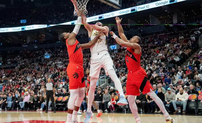 Indiana Pacers centre Jay Huff, center, drives to the hoop between Toronto Raptors forwards R.J. Barrett, left, and Scottie Barnes (4) during first-half NBA basketball game action in Toronto, Sunday Feb. 8, 2026. (Frank Gunn/The Canadian Press via AP)
