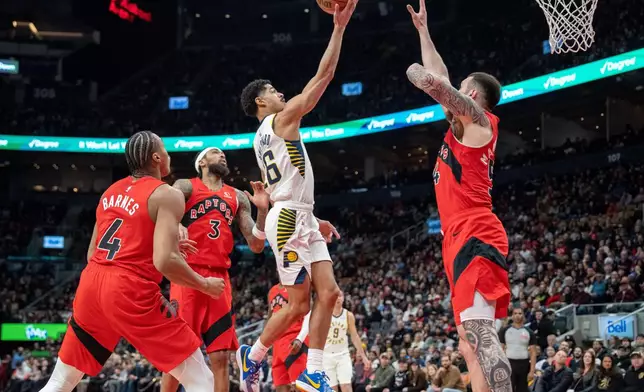 Indiana Pacers guard Ben Sheppard, center, goes to the hoop past Toronto Raptors' Brandon Ingram (3), Scottie Barnes (4) and Sandro Mamukelashvili, right, during first-half NBA basketball game action in Toronto, Sunday Feb. 8, 2026. (Frank Gunn/The Canadian Press via AP)