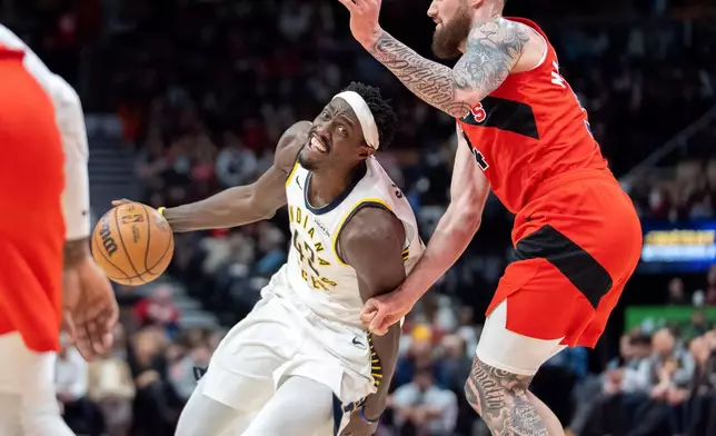 Indiana Pacers forward Pascal Siakam, left, drives past Toronto Raptors forward Sandro Mamukalashvili, right, during first-half NBA basketball game action in Toronto, Sunday Feb. 8, 2026. (Frank Gunn/The Canadian Press via AP)