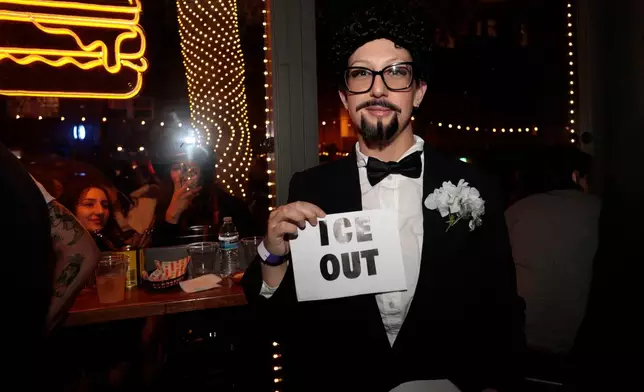 A contestant at the Bad Bunny look-alike contestholds an "ICE OUT" sign throughout the evening at Tacolicious in San Francisco, Thursday, Feb. 5, 2026. (Giselle Garza Lerma/San Francisco Chronicle via AP)