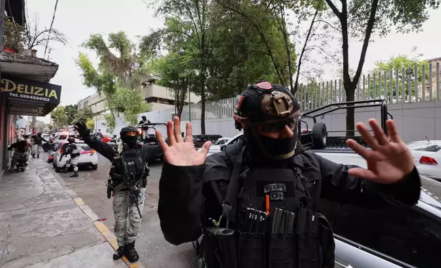 National Guards remove pedestrians by the General Prosecutor's headquarters in Mexico City, Sunday, Feb. 22, 2026, after the death of the leader of the Jalisco New Generation Cartel, Nemesio Rubén Oseguera Cervantes, known as "El Mencho." (AP Photo/Ginette Riquelme)