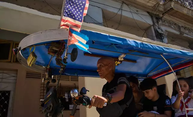 A driver steers his bicycle taxi decorated with U.S. and Cuban flags in Havana, Cuba, Monday, Feb. 16, 2026. (AP Photo/Ramon Espinosa)
