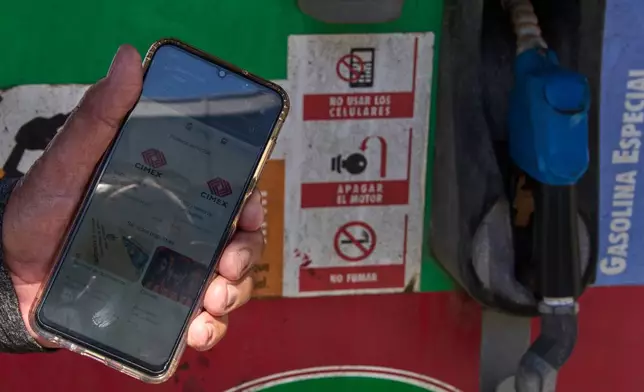 Retiree Jorge Reyes shows his phone with the app "El Ticket" which is used to reserve a place in line to buy rationed gasoline in Havana, Cuba, Monday, Feb. 16, 2026. (AP Photo/Ramon Espinosa)