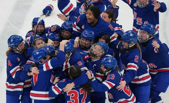 United States players surround Megan Keller (5) after she scored the winning goal in overtime to beat Canada in the women's ice hockey gold medal game at the 2026 Winter Olympics, in Milan, Italy, Feb. 19, 2026. (AP Photo/Carolyn Kaster, File)