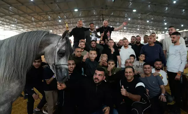 Owners and trainers pose with their trophy winner, stallion RDS Leon, born in 2022 and a gold champion in his class, during the third and final day of the 18th Palestine Championship for Purebred Arabian Horses, in the West Bank city of Jericho, Saturday, Feb. 14, 2026. (AP Photo/Nasser Nasser)