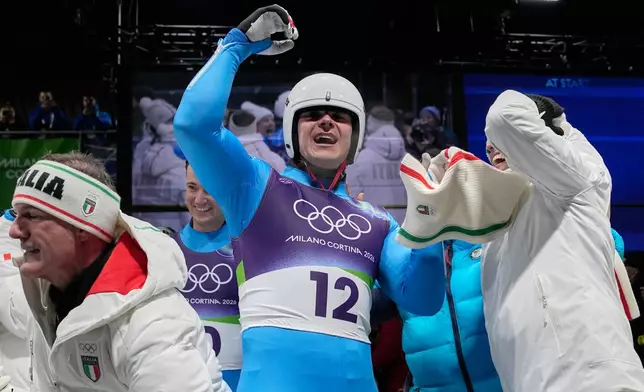 Italy's Dominik Fischnaller, center, celebrates winning the bronze medal as he arrives at the finish during a men's single luge run at the 2026 Winter Olympics, in Cortina d'Ampezzo, Italy, Sunday, Feb. 8, 2026. (AP Photo/Alessandra Tarantino)