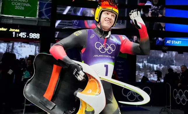 Germany's Max Langenhan waves as he arrives at the finish during a men's single luge run at the 2026 Winter Olympics, in Cortina d'Ampezzo, Italy, Sunday, Feb. 8, 2026. (AP Photo/Alessandra Tarantino)