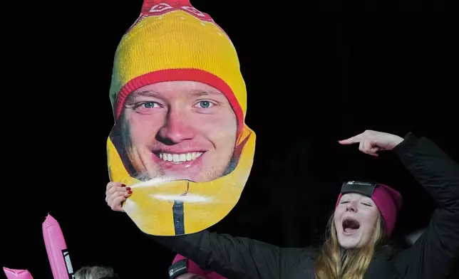 A person holds a giant portrait of Germany's Max Langenhan in the finish area during a men's single luge run at the 2026 Winter Olympics, in Cortina d'Ampezzo, Italy, Sunday, Feb. 8, 2026. (AP Photo/Alessandra Tarantino)