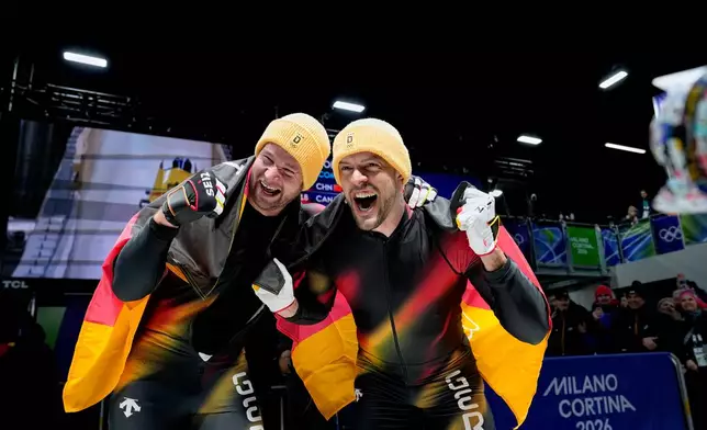 Germany's gold medalists Johannes Lochner, left, and Georg Fleischhauer celebrate at the finish after the two man bobsled competition at the 2026 Winter Olympics, in Cortina d'Ampezzo, Italy, Tuesday, Feb. 17, 2026. (AP Photo/Alessandra Tarantino)