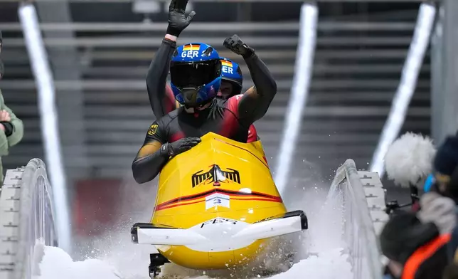Germany's Adam Ammour, front, and Alexander Schaller arrive at the finish during a two man bobsled run at the 2026 Winter Olympics, in Cortina d'Ampezzo, Italy, Tuesday, Feb. 17, 2026. (AP Photo/Aijaz Rahi)