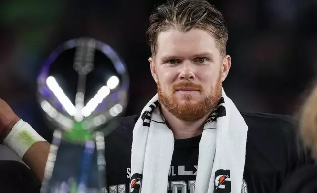 Seattle Seahawks quarterback Sam Darnold eyes the Lombardi Trophy after a win over the New England Patriots in the NFL Super Bowl 60 football game Sunday, Feb. 8, 2026, in Santa Clara, Calif. (AP Photo/Matt Slocum)