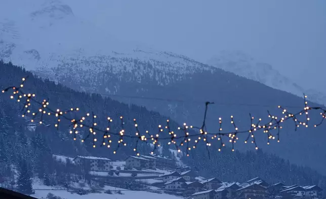 Houses perched on the mountain alongside Stelvio Ski Centre are seen past town lights in Bormio, Italy, at the 2026 Winter Olympics, Wednesday, Feb. 4, 2026. (AP Photo/Rebecca Blackwell)
