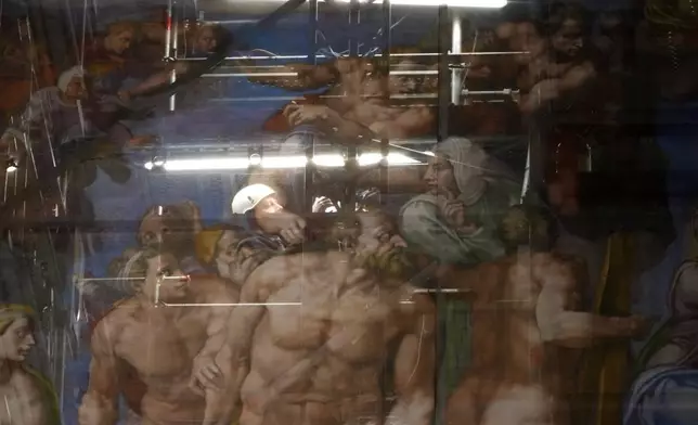 A man walks behind a screen with a replica of “The Last Judgment,” superimposed on it that covers the scaffolding used for its extraordinary maintenance during a presentation for press in the Sistine Chapel at the Vatican, Saturday, Feb. 28, 2026. (AP Photo/Alessandra Tarantino)