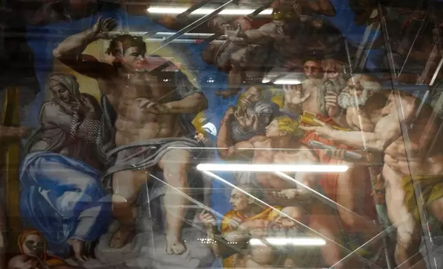A woman walks behind a screen with a replica of “The Last Judgment,”superimposed on it that covers the scaffolding used for its extraordinary maintenance during a presentation for press in the Sistine Chapel at the Vatican, Saturday, Feb. 28, 2026. (AP Photo/Alessandra Tarantino)