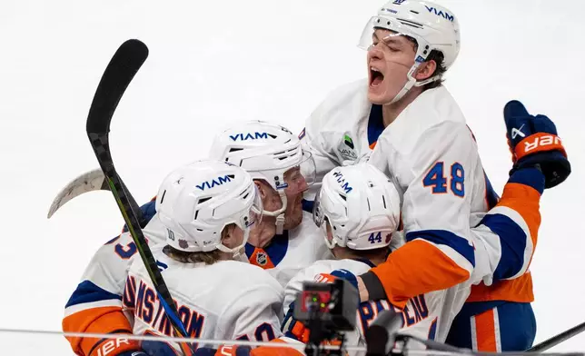 New York Islanders' Jean-Gabriel Pageau (44) celebrates after his winning goal with teammates Simon Holmstrom (10), Casey Cizikas, second from left, and Matthew Schaefer (48) during overtime NHL hockey game action in Montreal, Thursday, Feb. 26, 2026. (Christinne Muschi/The Canadian Press via AP)