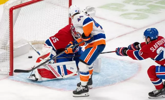 New York Islanders' Jean-Gabriel Pageau (44) scores on Montreal Canadiens goaltender Samuel Montembeault (35) during the overtime of an NHL hockey game in Montreal, Thursday, Feb. 26, 2026. (Christinne Muschi/The Canadian Press via AP)