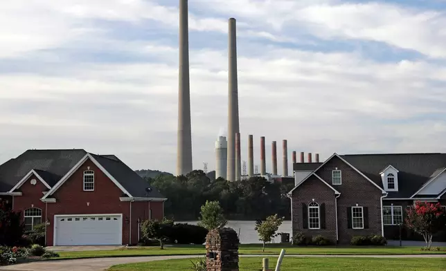 FILE - The Kingston Fossil Plant smokestacks rise above the trees behind homes in Kingston, Tenn, Aug. 7, 2019. (AP Photo/Mark Humphrey, File)