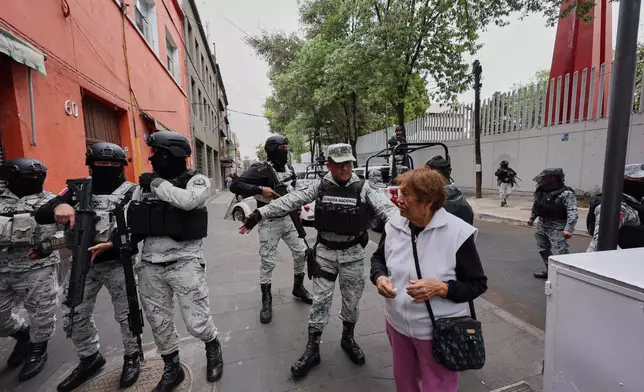 National Guards remove a pedestrian around the General Prosecutor's headquarters in Mexico City, Sunday, Feb. 22, 2026, after the death of the leader of the Jalisco New Generation Cartel, Nemesio Rubén Oseguera Cervantes, known as "El Mencho." (AP Photo/Ginette Riquelme)