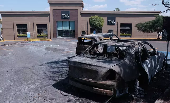 Charred vehicles sit in a parking lot sit outside a shopping mall in Guadalajara, Jalisco state, Mexico, Sunday, Feb. 22, 2026, as authorities reported that the Mexican Army killed Jalisco New Generation Cartel leader Nemesio Oseguera, known as "El Mencho." (AP Photo/Alejandra Leyva)