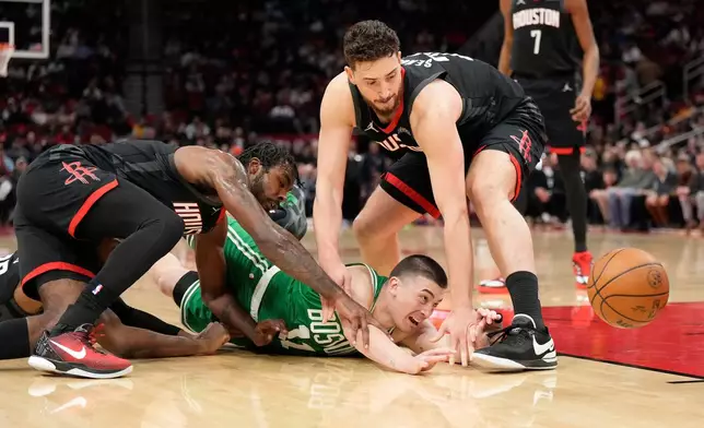 Boston Celtics guard Payton Pritchard loses control of the ball against Houston Rockets' Tari Eason, left, and Alperen Sengun, right, during the first half of an NBA basketball game, in Houston, Wednesday, Feb. 4, 2026. (AP Photo/ Karen Warren)