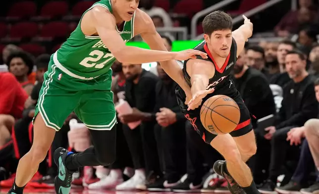 Houston Rockets guard Reed Sheppard, right, reaches for a loose ball against Boston Celtics forward Jordan Walsh (27) during the first half of an NBA basketball game, in Houston, Wednesday, Feb. 4, 2026. (AP Photo/ Karen Warren)