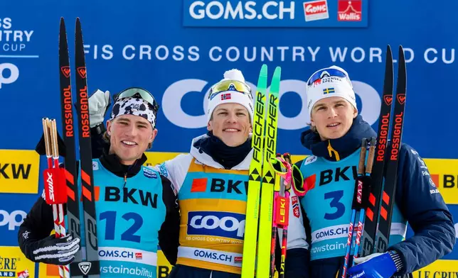 Winner Johannes Hoesflot Klaebo of Norway, centre, second placed Gus Schumacher of United States, left, and Edvin Anger of Sweden, right, celebrate on the podium after the men's sprint final classic skiing race, during the FIS Cross-Country World Cup at the Nordic Center Goms, in Geschinen, Switzerland, Saturday, Jan. 24, 2026. (Salvatore Di Nolfi/Keystone via AP)