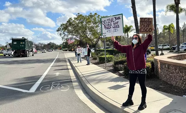Demonstrators hold signs outside a police station on Wednesday, Feb. 18, 2026 in Escondido, Calif. (AP Photo/Amy Taxin)