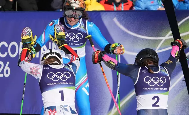 Sweden's Sara Hector, right, and Norway's Thea Louise Stjernesund bow to Italy's Federica Brignone, center, at the finish area of an alpine ski, women's giant slalom race, at the 2026 Winter Olympics, in Cortina d'Ampezzo, Italy, Sunday, Feb. 15, 2026. (AP Photo/Jacquelyn Martin)