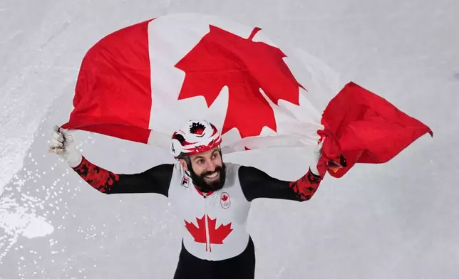 Steven Dubois of Canada celebrates the gold gold after the short track speed skating men's 500m final at the 2026 Winter Olympics, in Milan, Italy, Wednesday, Feb. 18, 2026.(AP Photo/Bernat Armangue)