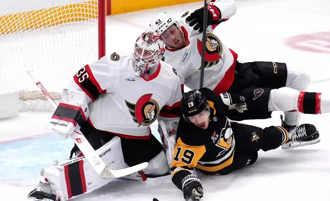 Ottawa Senators' Tyler Kleven (43) and Pittsburgh Penguins' Connor Dewar (19) collide with Senators goaltender Linus Ullmark (35) during the first period of an NHL hockey game in Pittsburgh, Monday, Feb. 2, 2026. (AP Photo/Gene J. Puskar)
