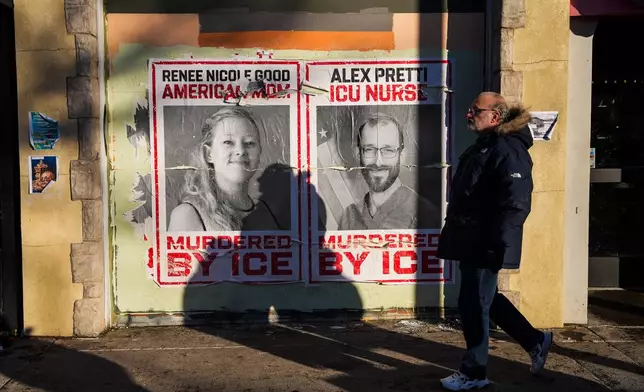 A man walks by posters of Renee Nicole Good and Alex Pretti, who were both fatally shot by federal agents, in Minneapolis, Saturday, Jan. 31, 2026. (AP Photo/Ryan Murphy)