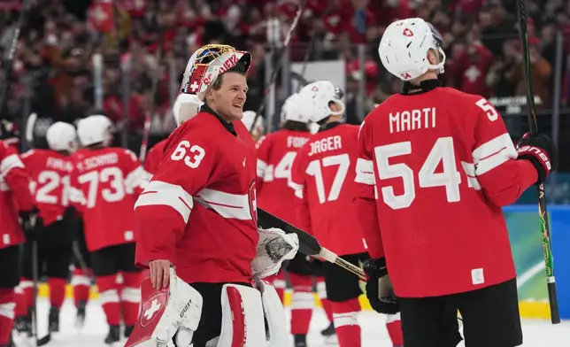 Switzerland's goalkeeper Leonardo Genoni, right, celebrates with teammates after a preliminary round match of men's ice hockey between Switzerland and France at the 2026 Winter Olympics, in Milan, Italy, Thursday, Feb. 12, 2026. (AP Photo/Carolyn Kaster)