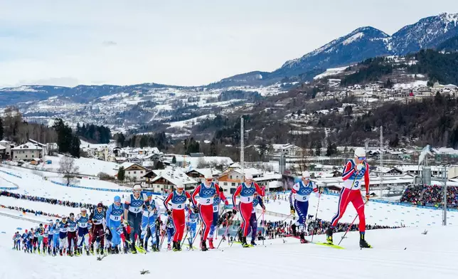 Martin Loewstroem Nyenget, of Norway, right, leads at the start of the cross country skiing men's 50km mass start Classic at the 2026 Winter Olympics, in Tesero, Italy, Saturday, Feb. 21, 2026. (AP Photo/Evgeniy Maloletka)